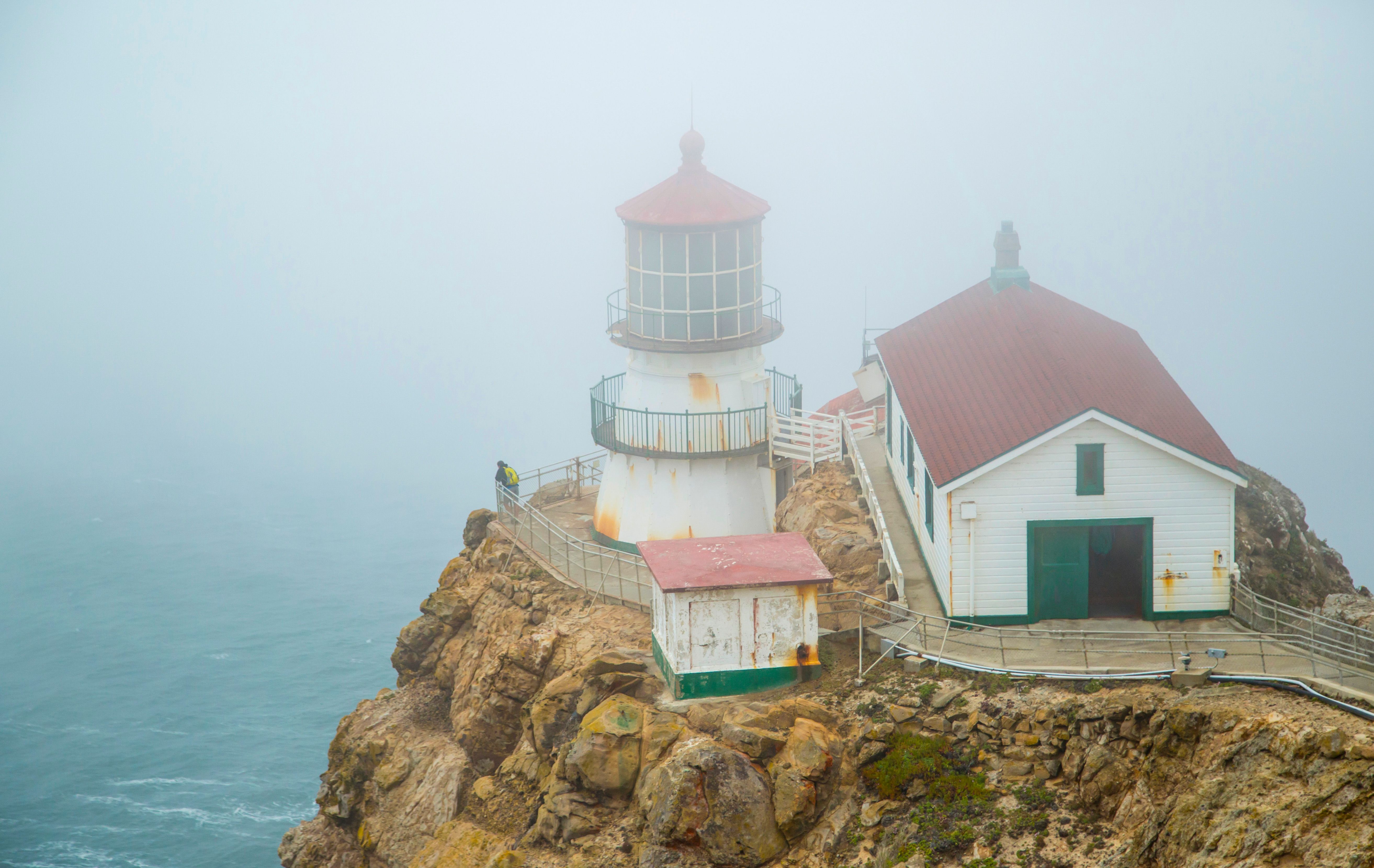 A misty scene of Point Reyes Lighthouse on a foggy day by the ocean.