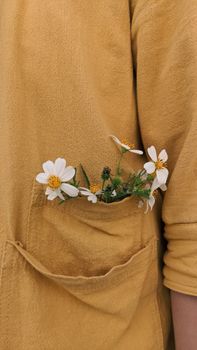 Close-up of small white flowers in a yellow jacket pocket, symbolizing simple creativity and natural beauty.