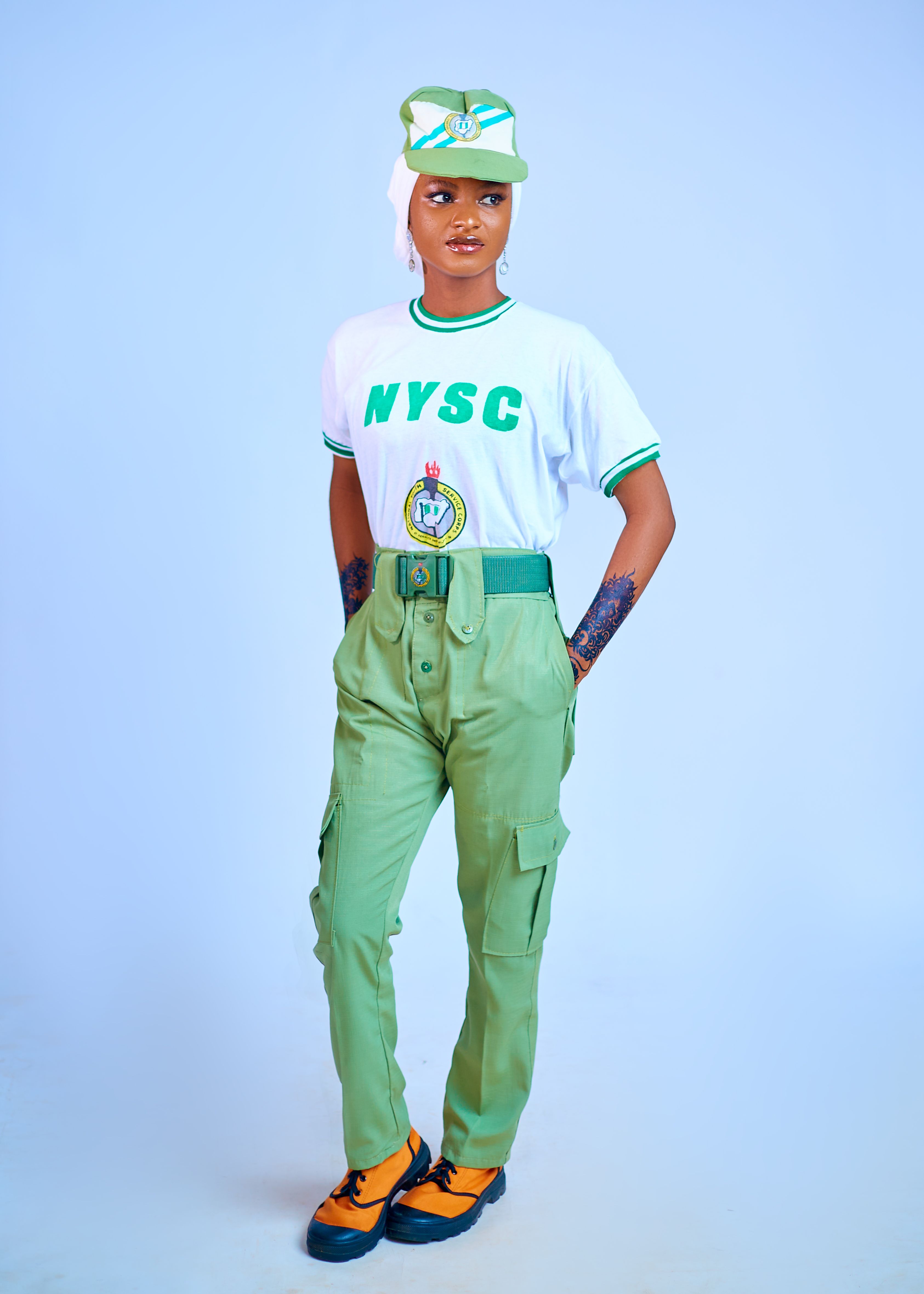 Young Nigerian adult in NYSC uniform standing front-facing indoors.