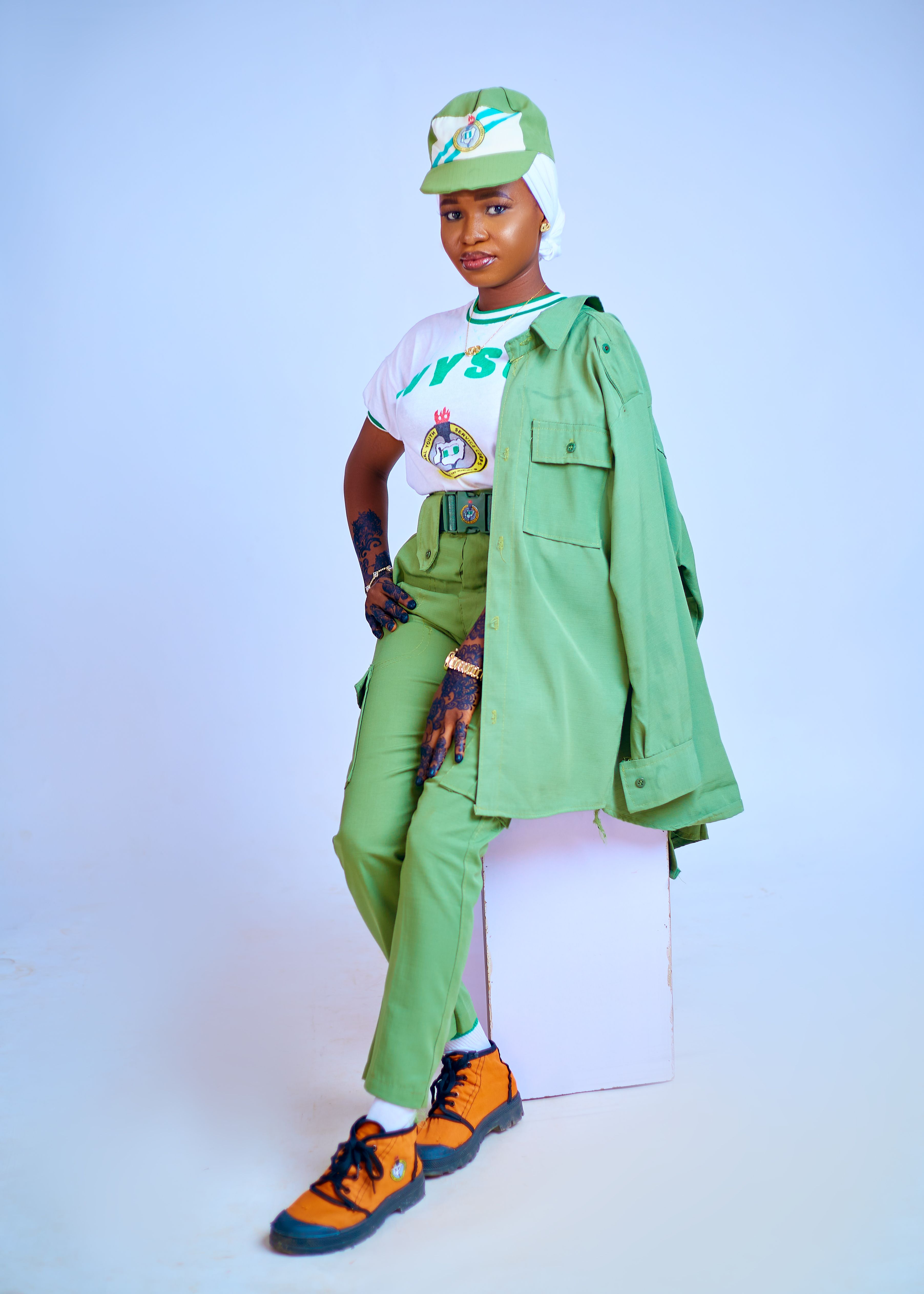 Portrait of a Nigerian youth corps member in official green uniform and cap.