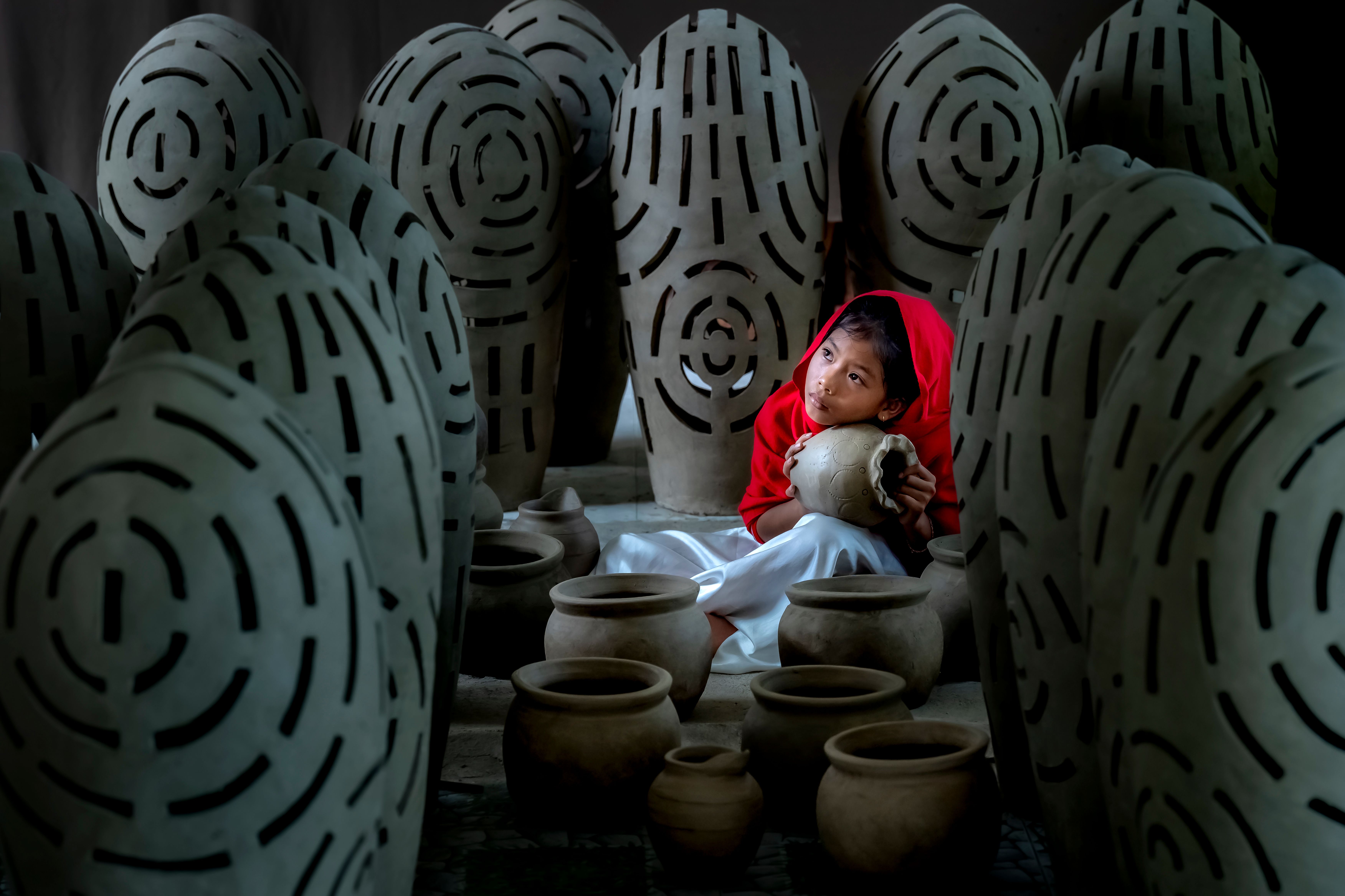 Child Pondering Among Artistic Clay Vases