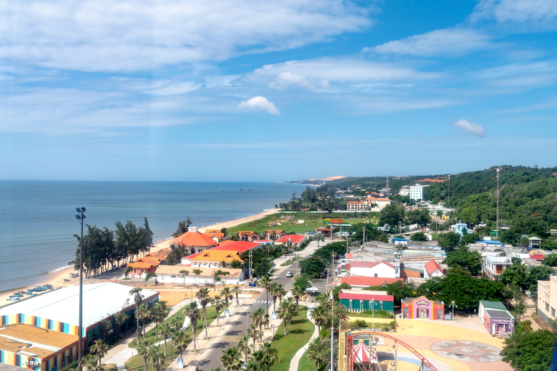Scenic aerial view of a vibrant beachfront town with colorful buildings along a tropical coast.