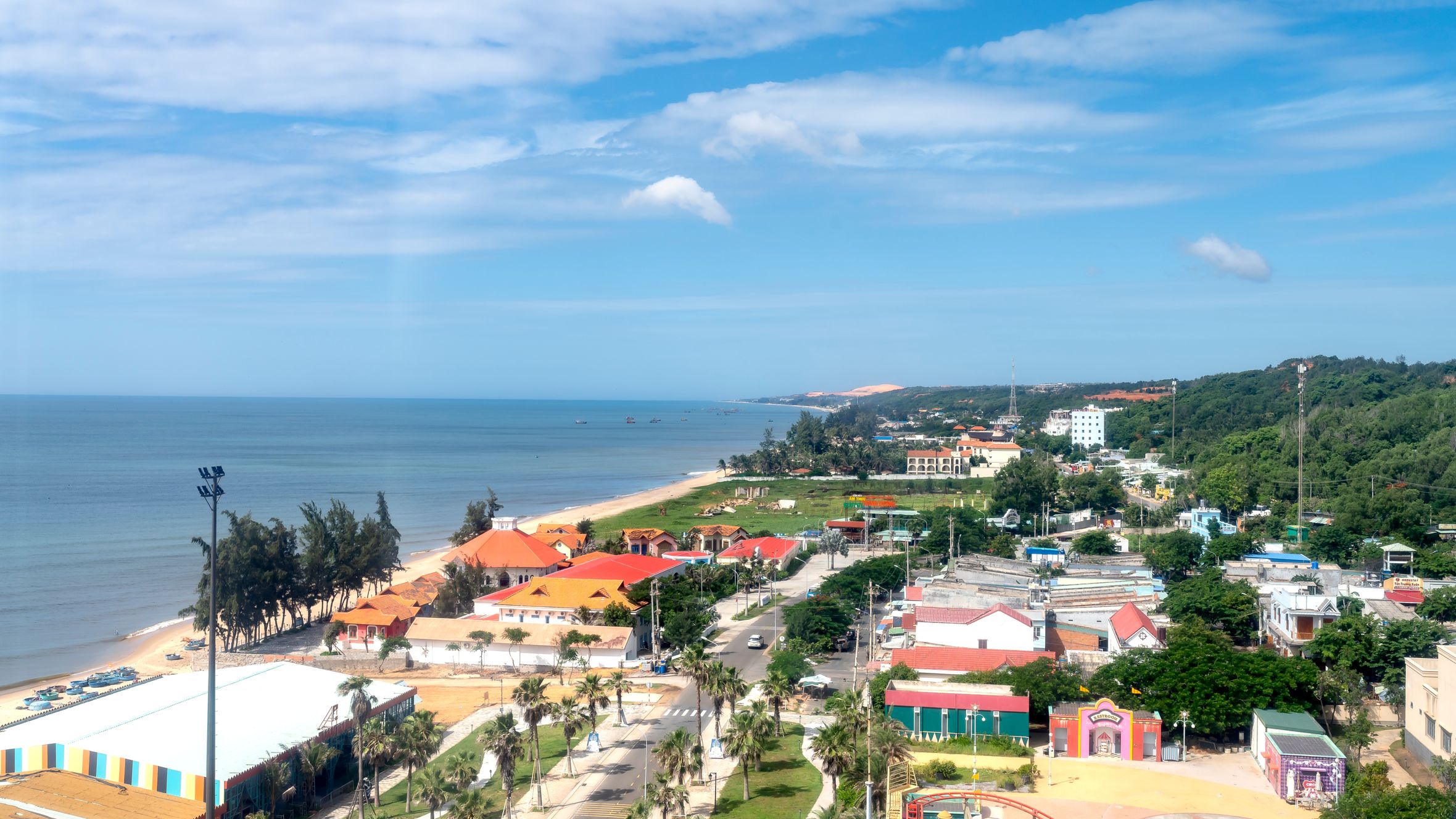 Scenic aerial view of a vibrant beachfront town with colorful buildings along a tropical coast.