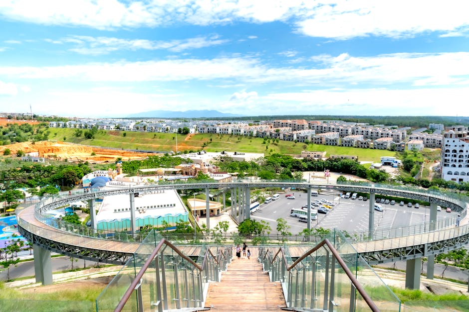 Aerial view of a modern park with a winding walkway and residential area in the distance.