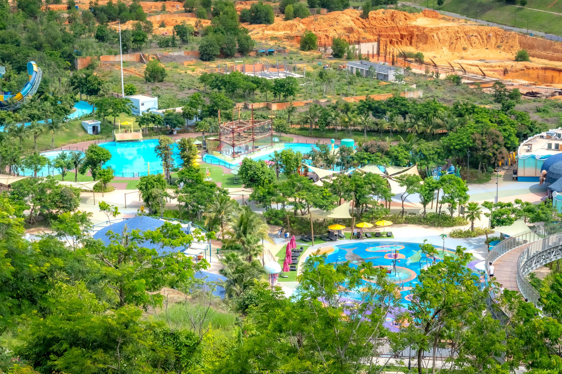 Aerial view of a colorful outdoor waterpark with lush greenery and attractions.