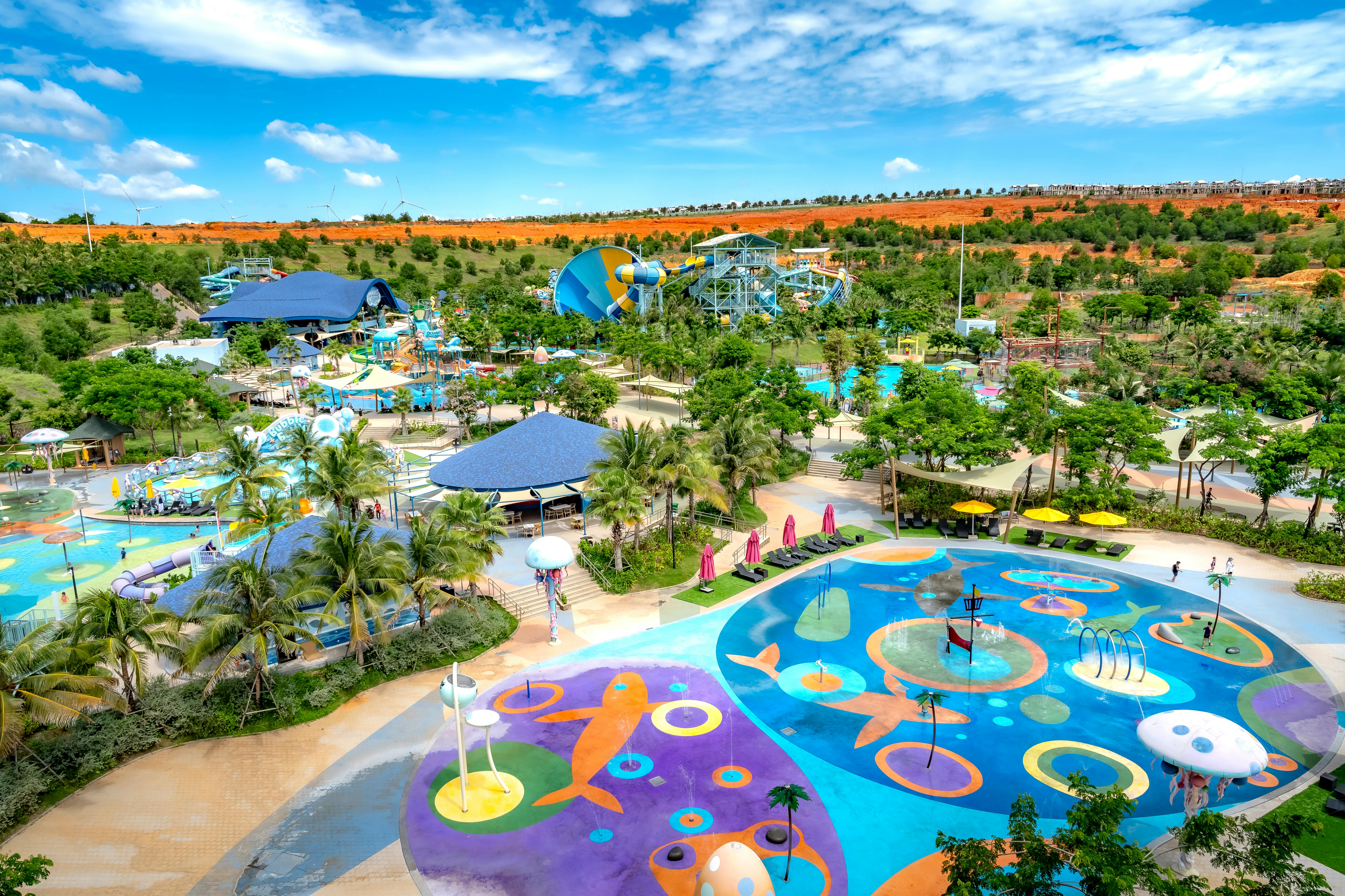 Aerial shot of a colorful and vibrant water park with pools and slides under a sunny sky.