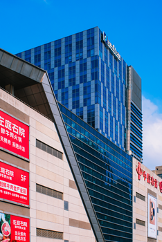Contemporary city building with striking blue glass facade and signage, under a clear sky.