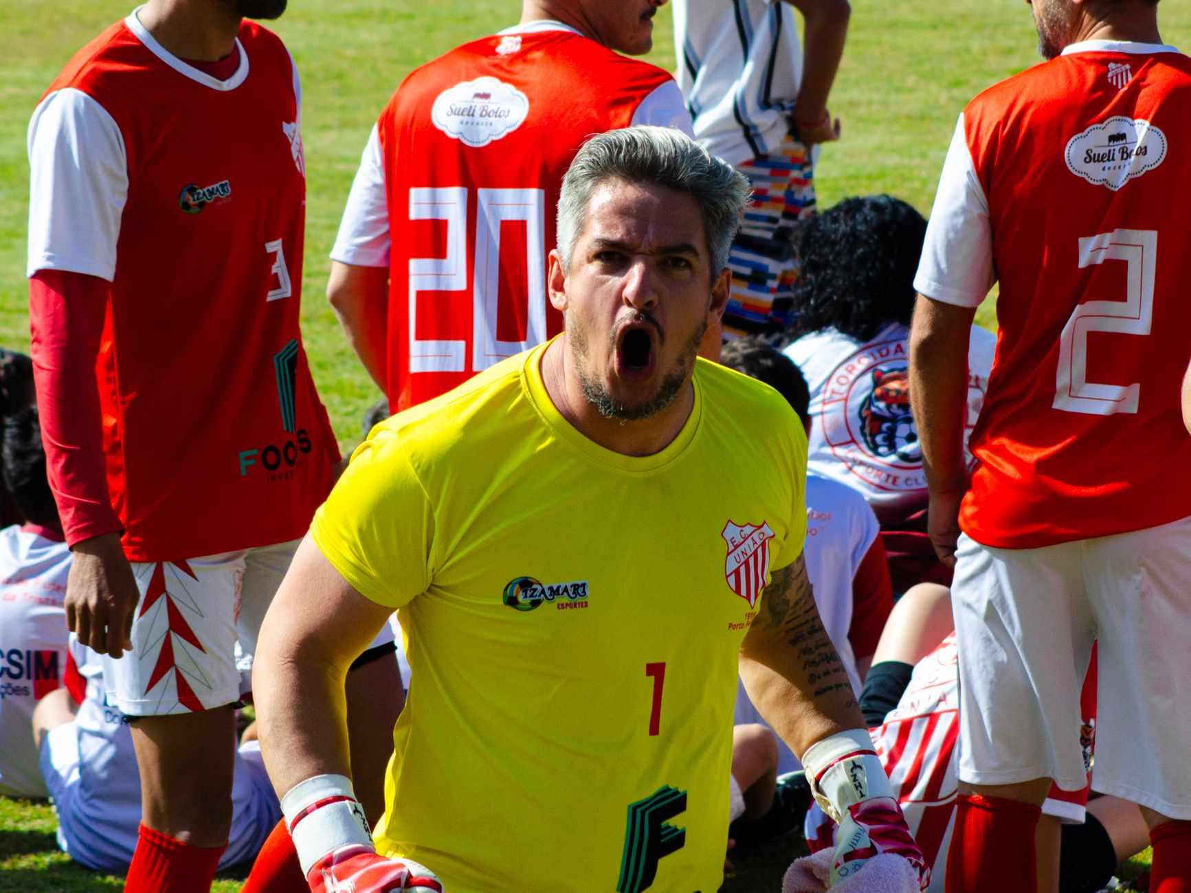 Goalkeeper in action with team during a competitive soccer match outdoors.