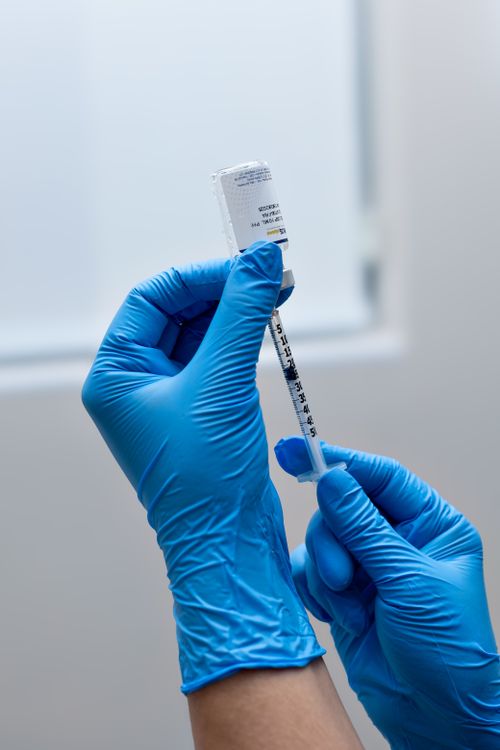 Free A healthcare worker prepares a syringe for vaccination in a medical setting. Stock Photo
