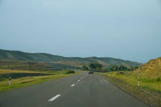 A peaceful road stretches through the lush, rolling hills under a clear sky.