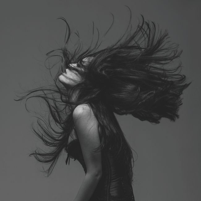 Striking black and white portrait of a woman flipping her hair, captured in a dynamic pose.