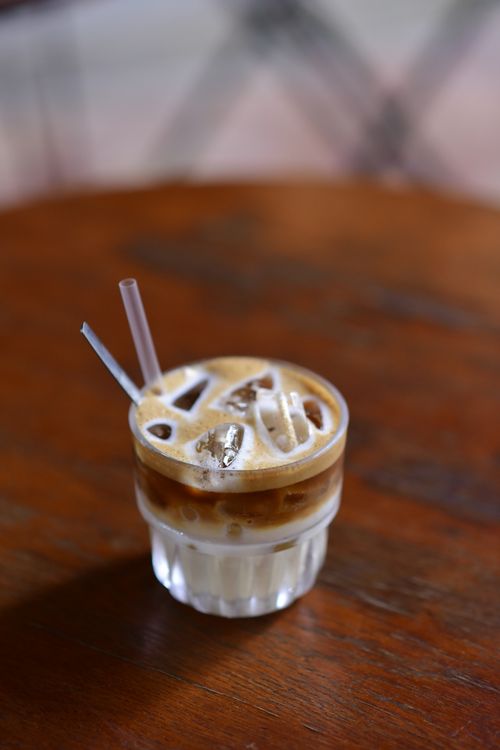 Free A glass of iced coffee with cream and straws on a rustic wooden table. Stock Photo