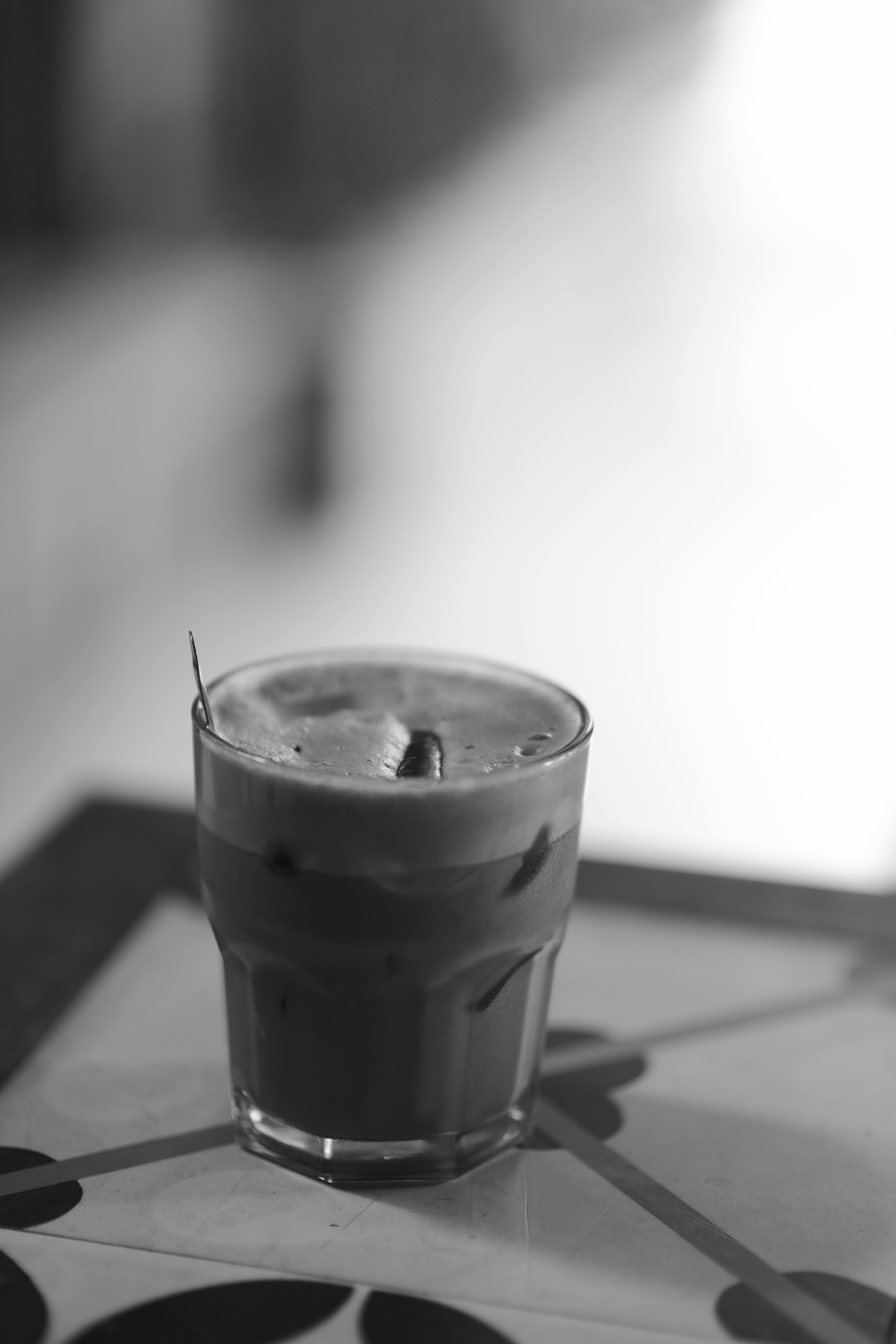 Gratuit Fotografie alb-negru a unui pahar de cafea cu gheață pe o masă cu model. Fotografie de stoc