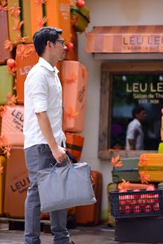 A man in a white shirt and gray pants holding a bag walks by a vibrant storefront display.
