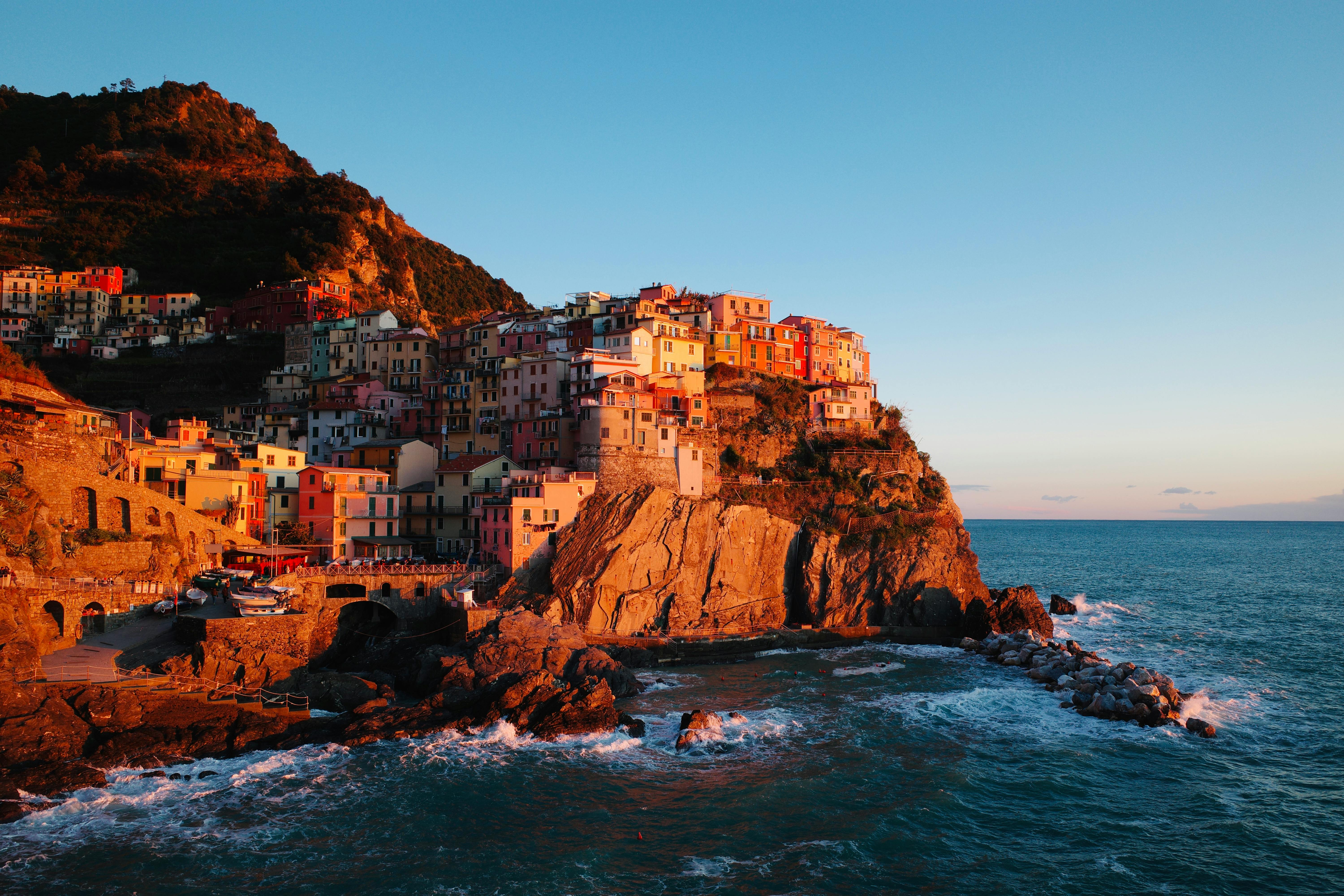 A stunning view of Manarola's colorful houses perched on cliffs overlooking the Ligurian Sea at sunset.