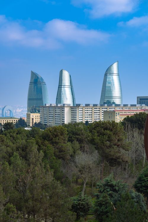 Free Scenic view of Baku's iconic Flame Towers with foreground greenery under a clear blue sky. Stock Photo