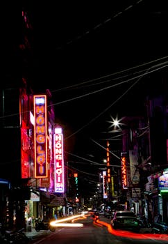 Dynamic city street with glowing neon signs and light trails capturing nightlife energy.