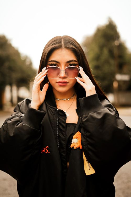 Free Fashionable young woman wearing sunglasses posing confidently outdoors. Stock Photo