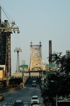 Cars drive across the Queensboro Bridge in New York City, framed by urban architecture.