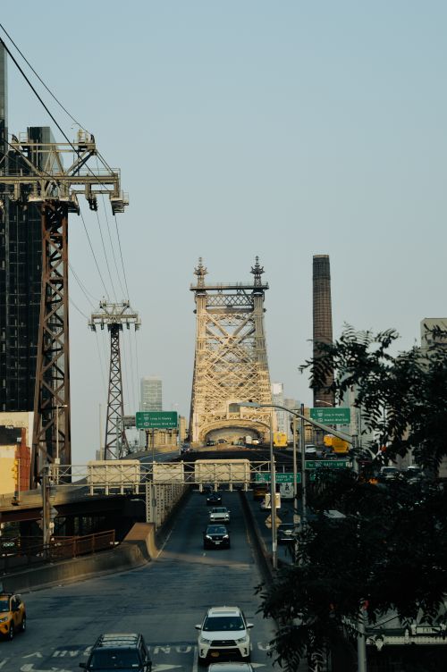 Free Cars drive across the Queensboro Bridge in New York City, framed by urban architecture. Stock Photo
