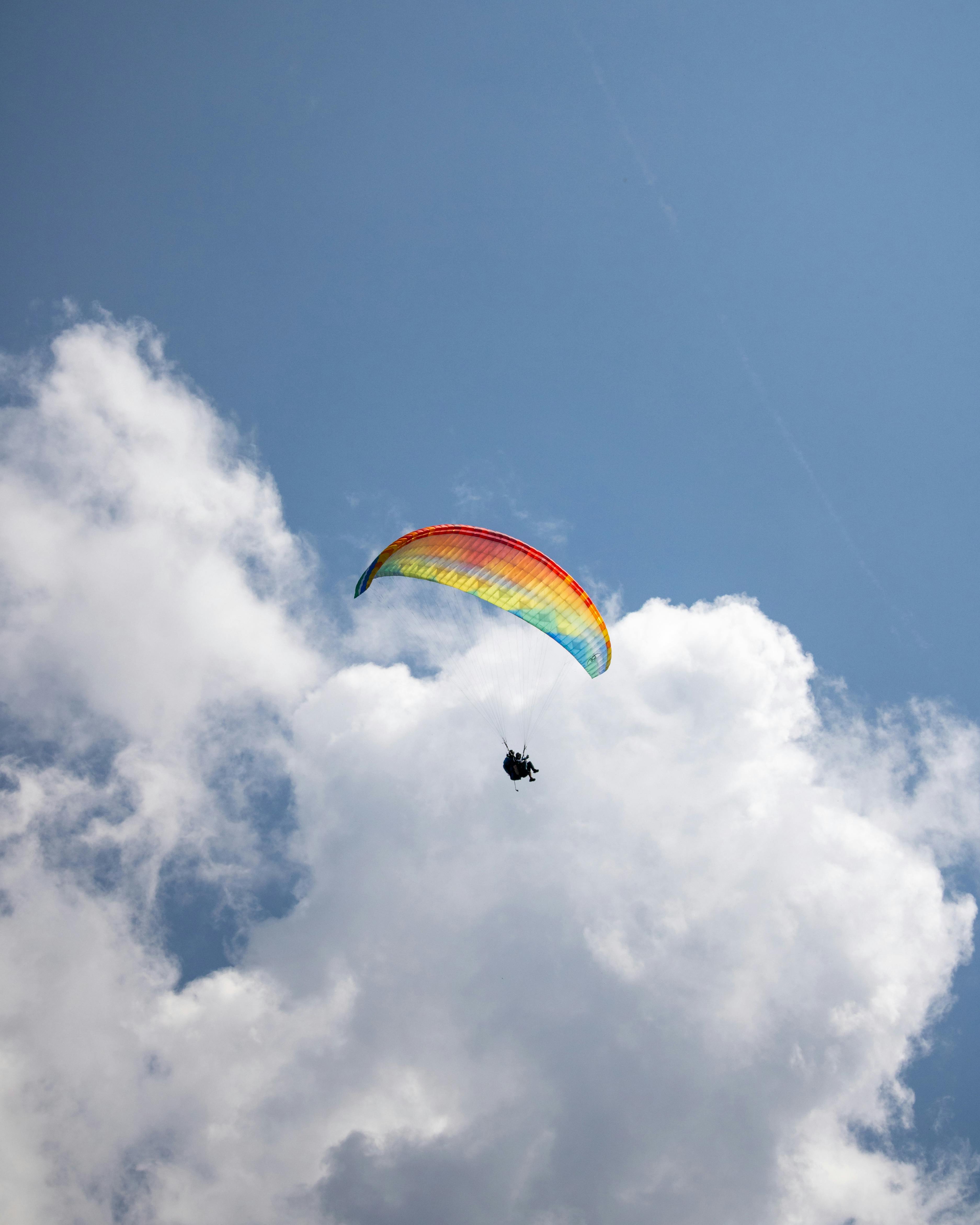 A vibrant paraglider soaring through clouds in Kühtai, Tirol, Austria.