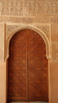 Stunning wooden arch door with ornate carvings in the Alhambra, showcasing Moorish architecture.