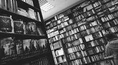 一张黑白图像中，有人在图书馆或书店里浏览书架