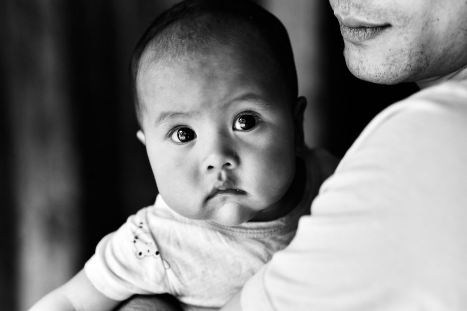 Intimate black and white portrait of a baby being held by a parent, capturing a tender moment.