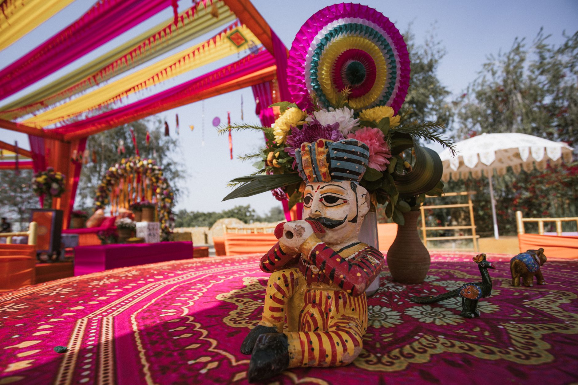 Vibrant Indian wedding setup with traditional decor and colorful flowers under a vivid canopy.