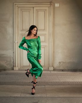 Stylish woman in a vibrant green dress posing outside a classic doorway in Munich, Germany.