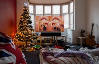 这间圣诞客厅温馨迷人，装点着亮灯的圣诞树和节日饰品，洋溢着舒适的氛围