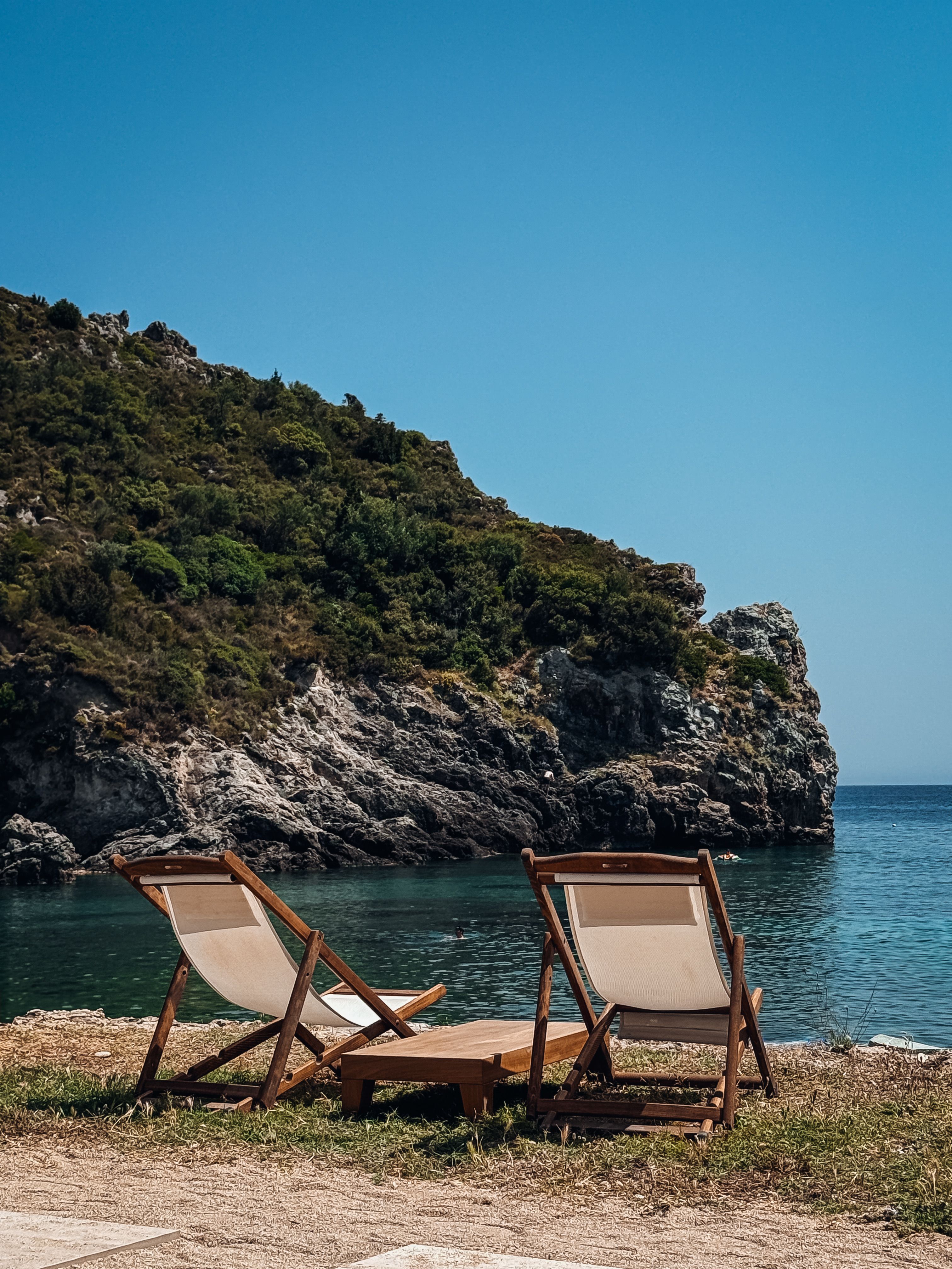 Relaxing seaside scene with sun loungers overlooking the blue waters and rocky cliffs of Corfu.
