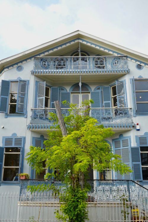 Free Elegant blue Victorian-style house with lush greenery and ornate balconies. Stock Photo