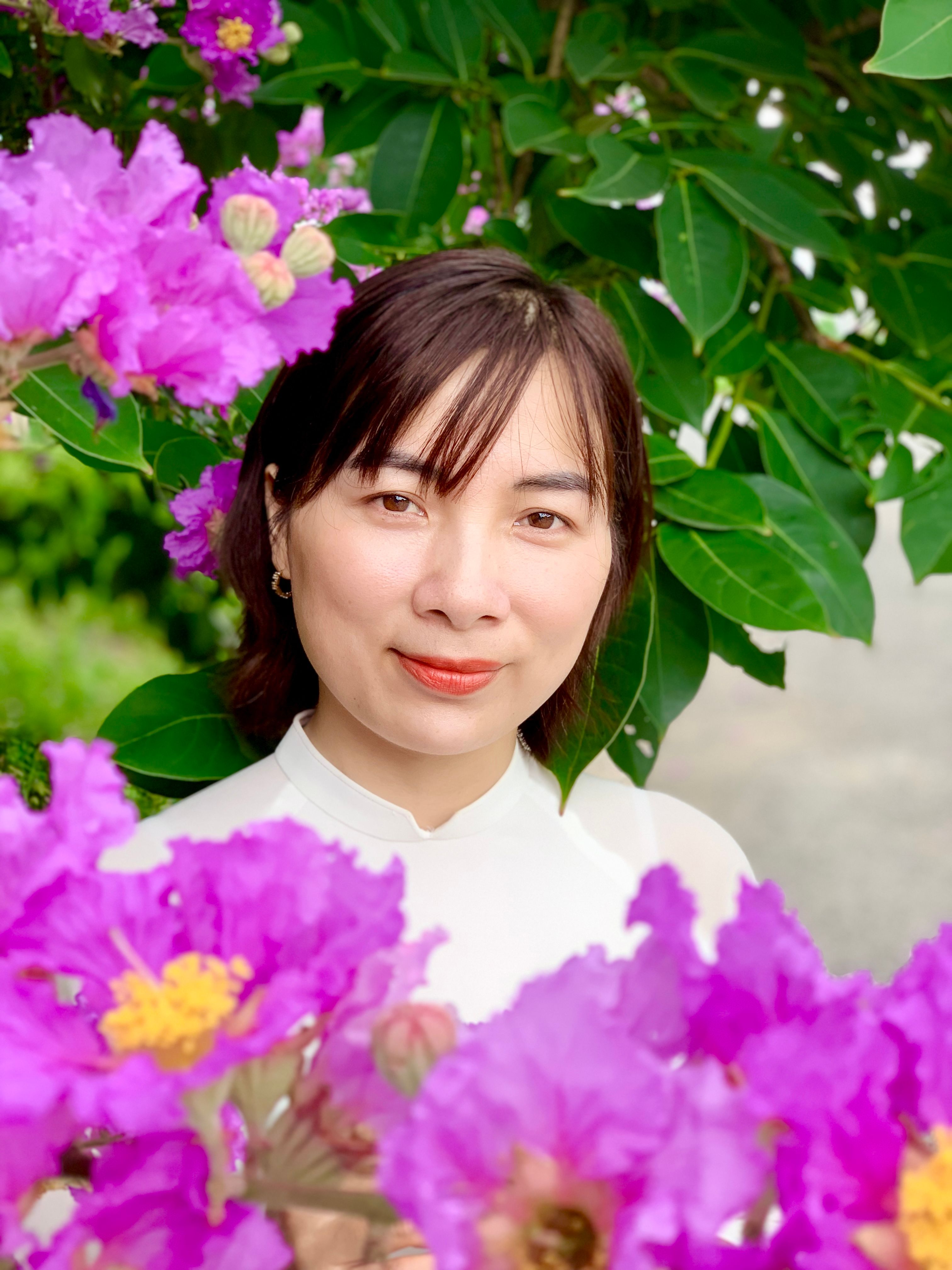 A serene portrait of a woman surrounded by vivid purple crape myrtle blooms outdoors.