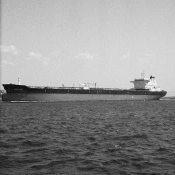 A large oil tanker ship navigates the open sea under a clear sky.