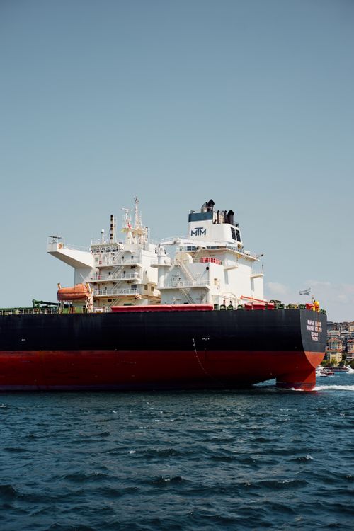 Free A large cargo ship sails on the open sea under a clear blue sky, showcasing maritime transport. Stock Photo