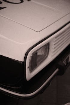 Close-up of a vintage car's headlight in sepia tone, evoking classic nostalgia.