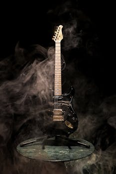 Striking black electric guitar enveloped in smoke on a circular platform, creating a mysterious musical vibe.