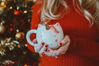 一名女子拿着一个独角兽主题的马克杯，杯子上有节日背景装饰