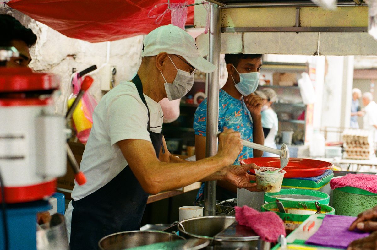 Pengendali gerai makanan Malaysia menyediakan pesanan di kaunter