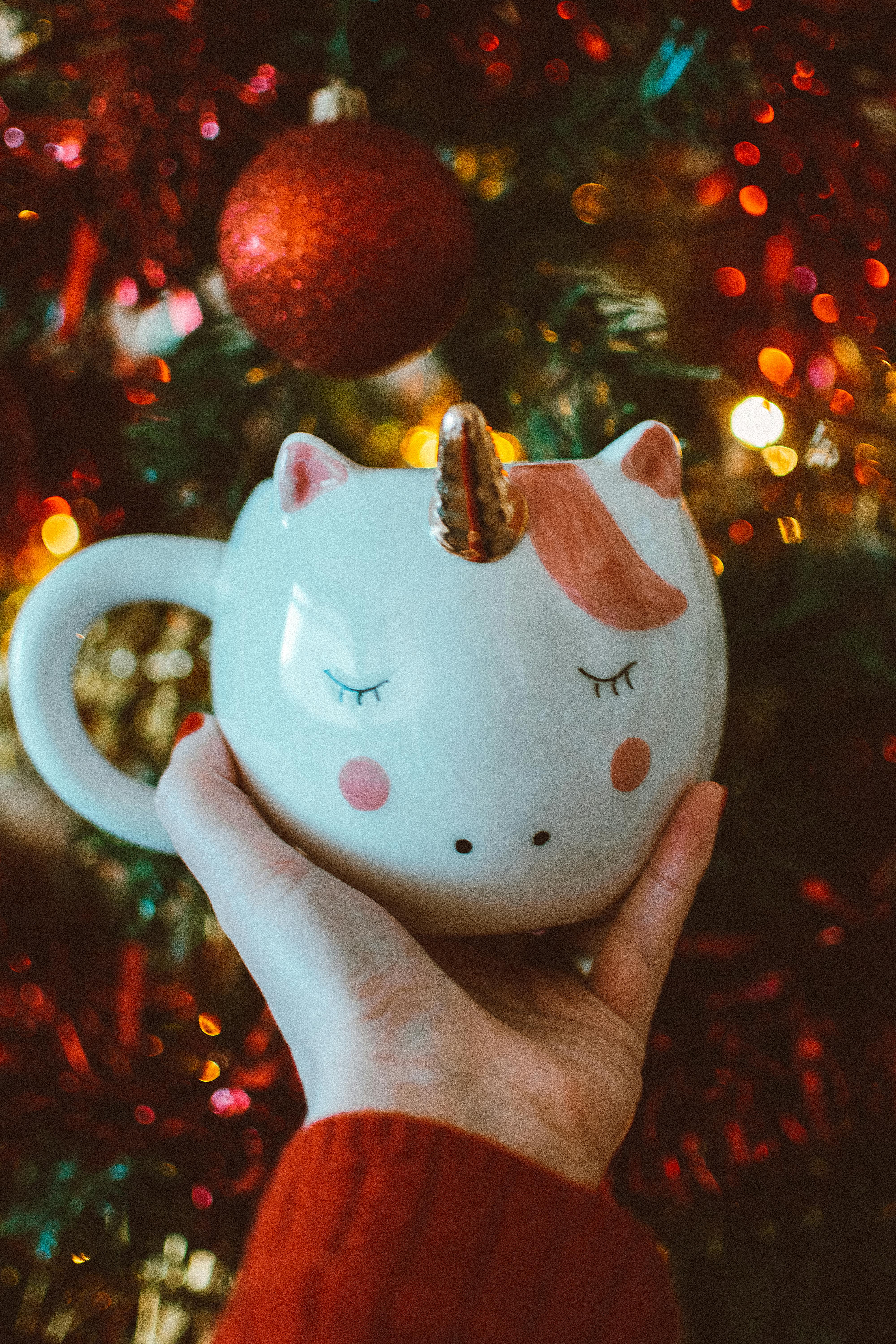 手拿独角兽杯站在节日的圣诞装饰品前