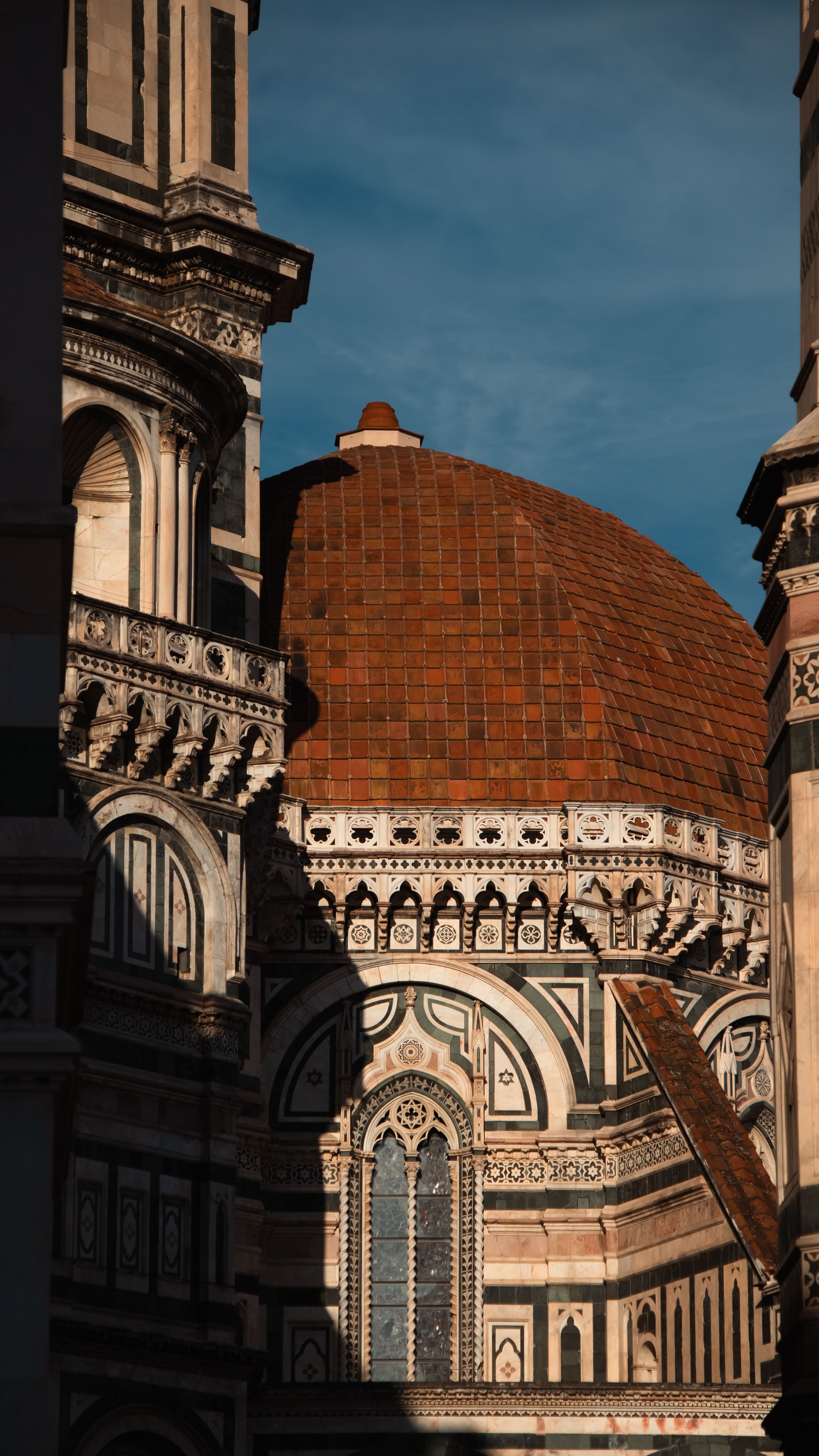 Close-up of the Florence Duomo's intricate architecture and terracotta dome at sunset.