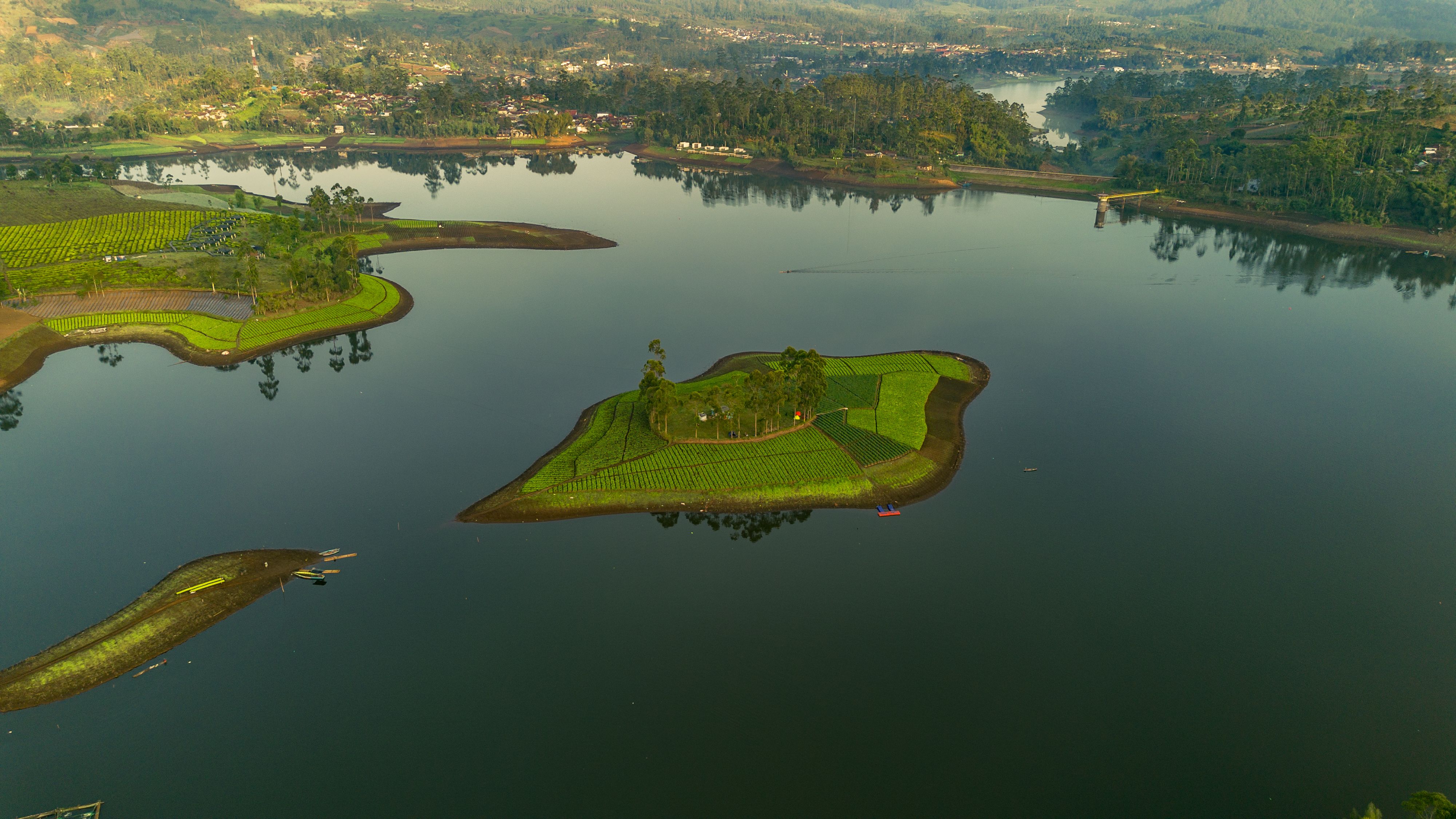 Aerial shot of a lush green island in a tranquil lake surrounded by nature, ideal for peaceful escapes.