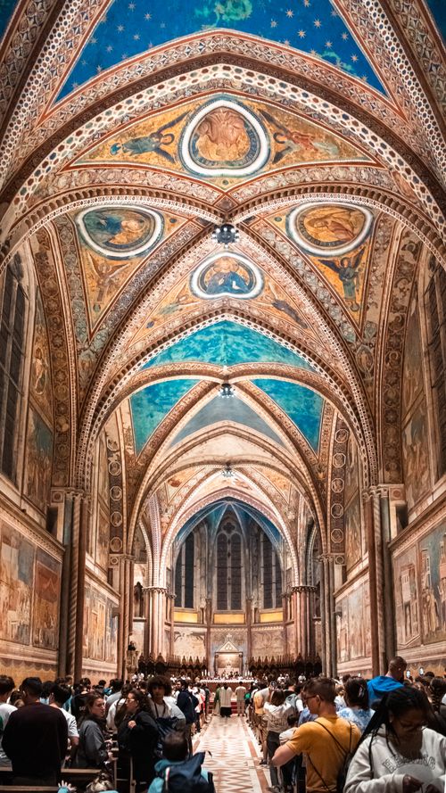 Free Intricate frescoes and architecture of Basilica in Assisi, Italy filled with visitors. Stock Photo