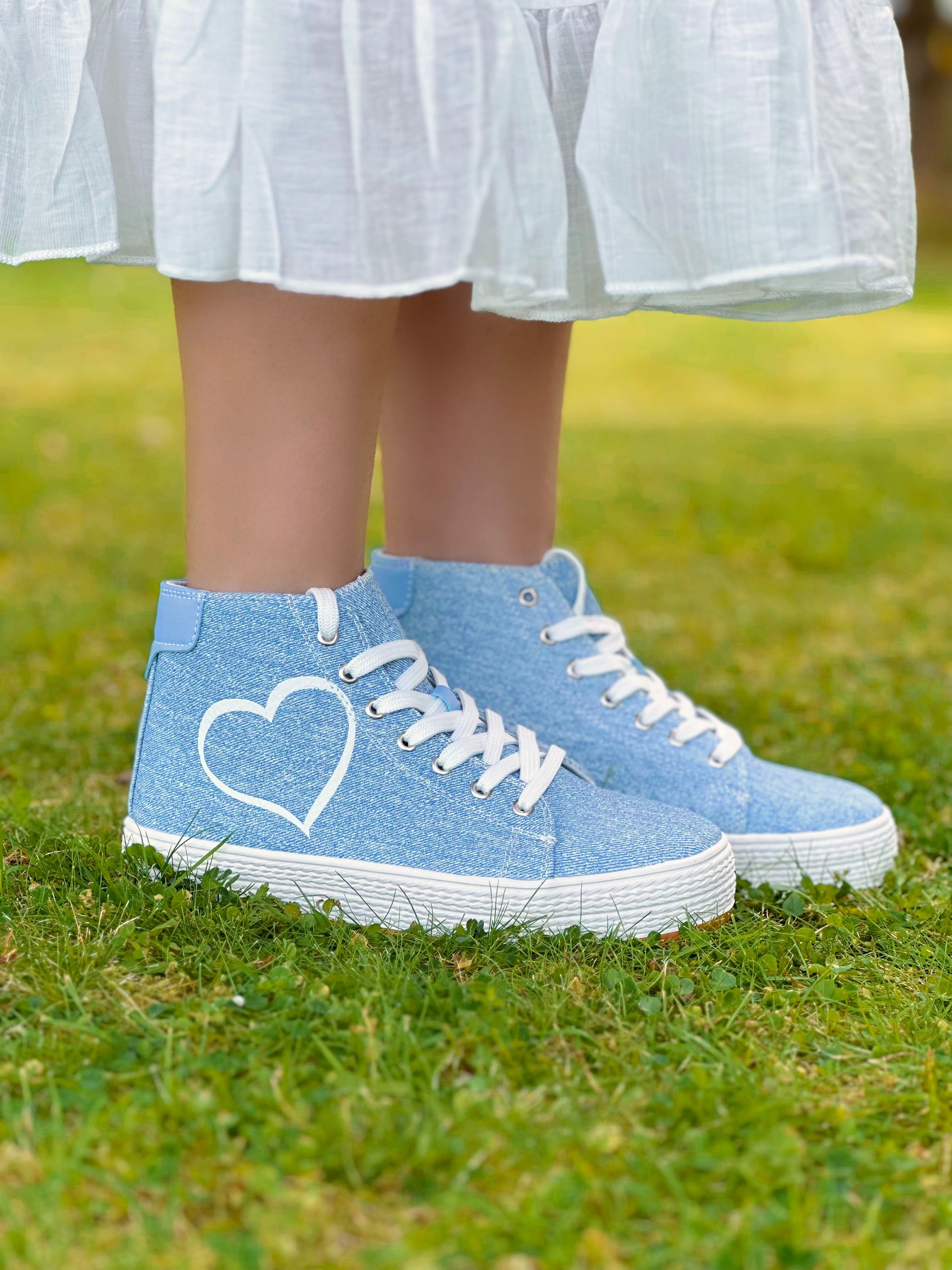 Pair of blue sneakers with heart design on grass background for casual outdoor look.