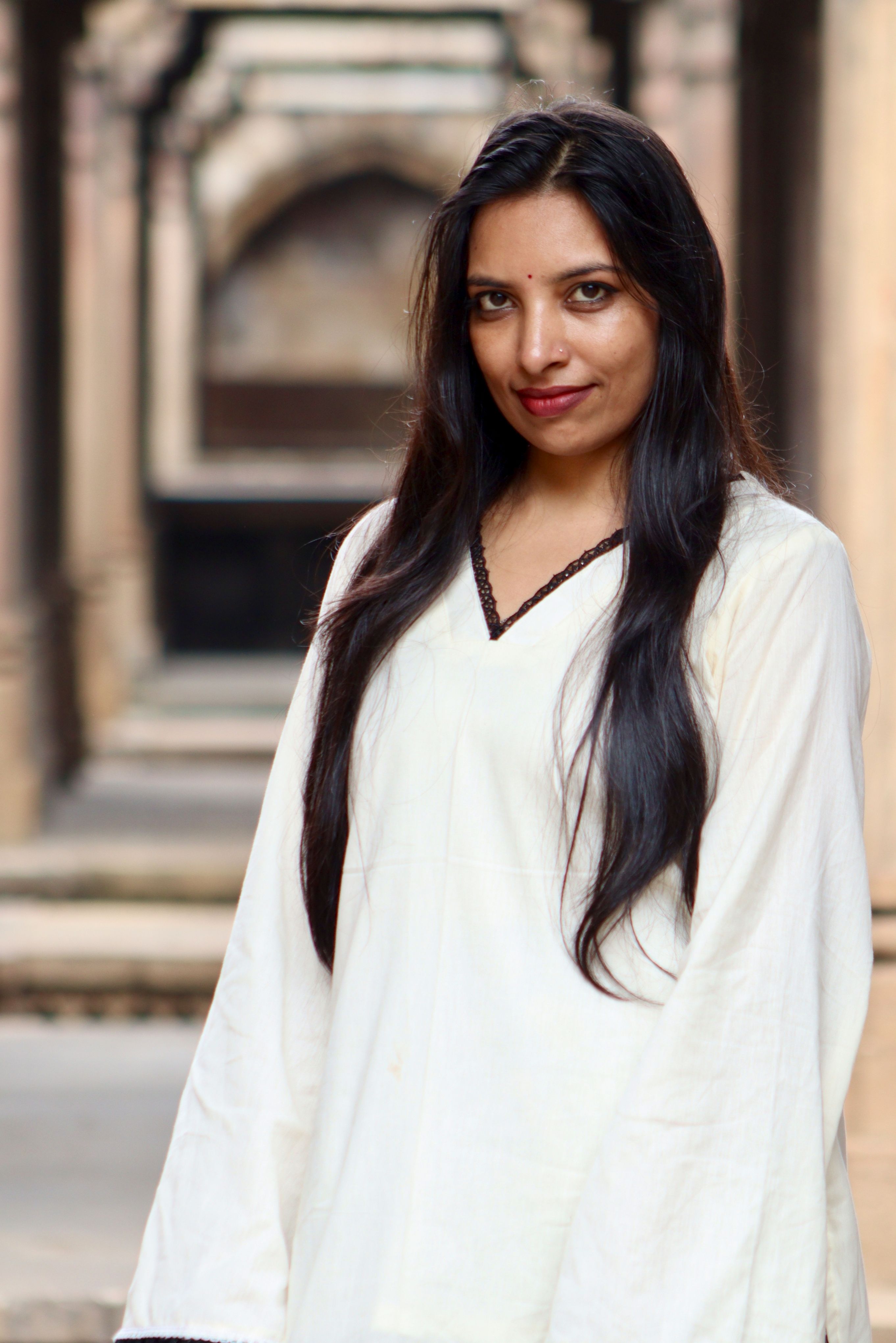 Portrait of a woman in traditional attire, captured against historic arched architecture.