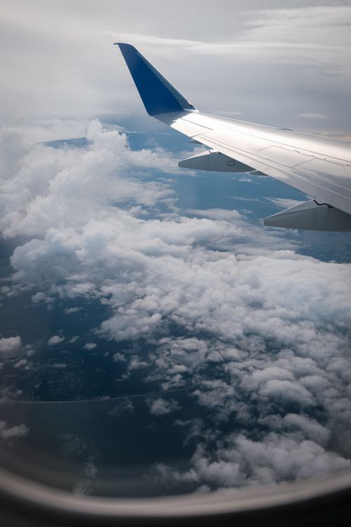 Free Scenic view from airplane window showcasing clouds and wing during daytime flight. Stock Photo