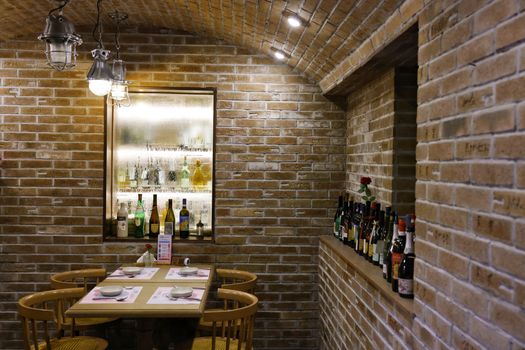 A warm and inviting wine cellar dining room with brick walls and a selection of wines on display.