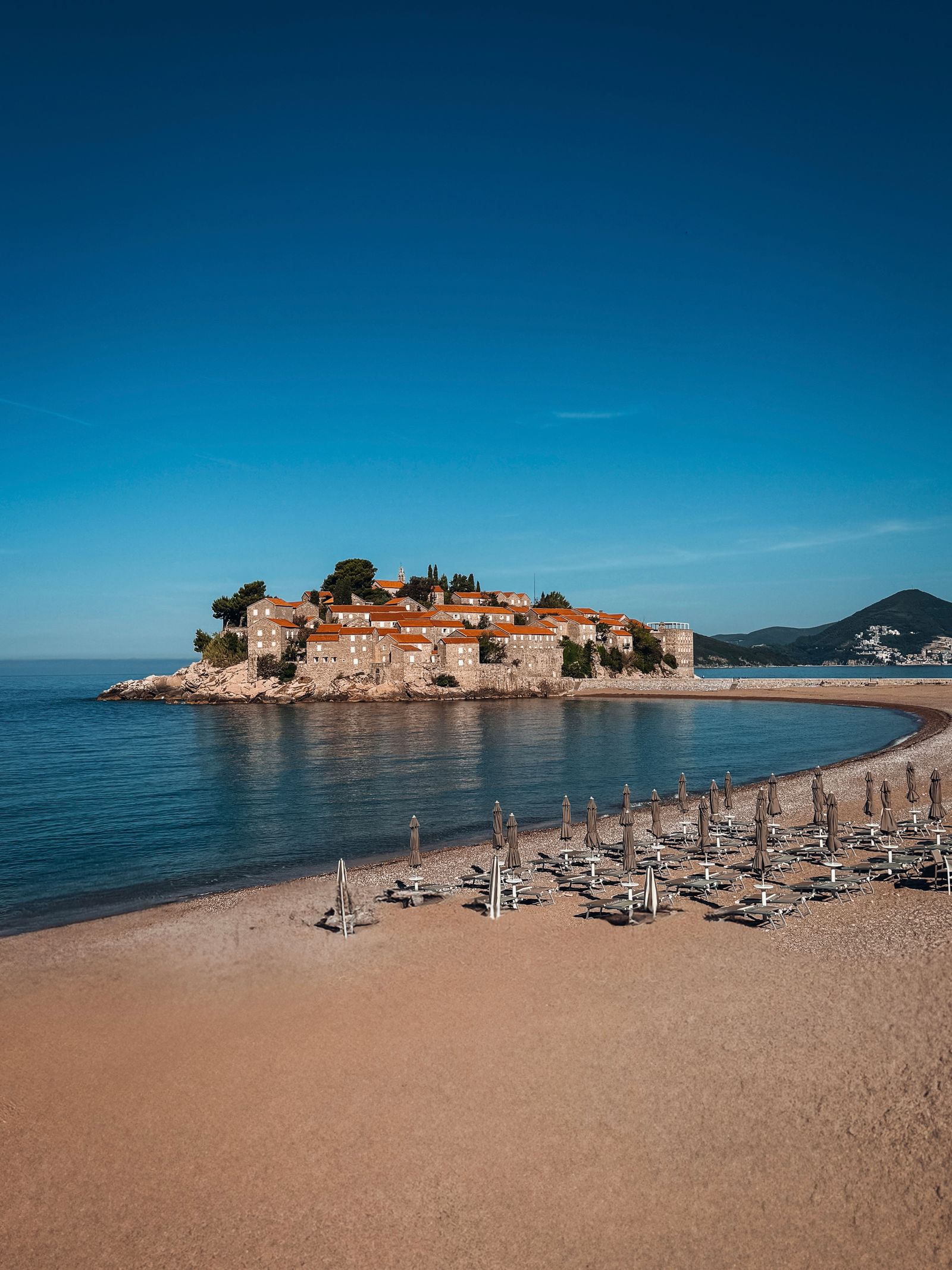 Aerial view of Sveti Stefan, Montenegro, with beach umbrellas and clear blue water