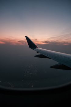 Stunning view of airplane wing during flight at sunset, displaying beautiful sky colors.